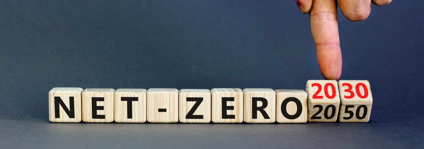 Wooden blocks spelling “NET-ZERO” with interchangeable cubes showing the years 2030 and 2050, symbolising climate targets and how battery energy storage can help, with a hand pointing to 2030.